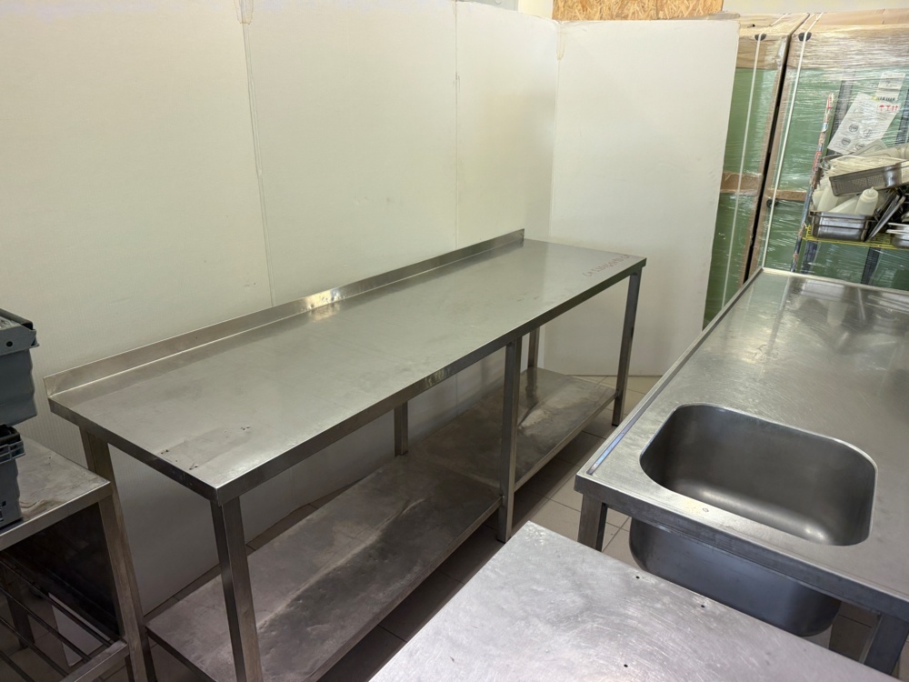 1141794-1 Stainless steel workbench with lower shelf, folded back edge. Approx. 230x65x90 cm